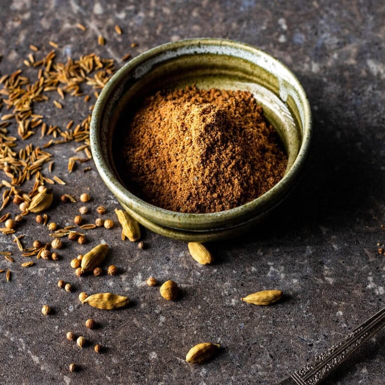 Green ceramic bowl of garam masala spice blend.