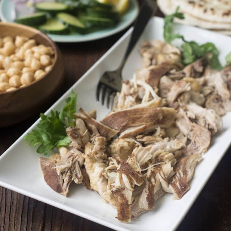 Shawarma chicken thighs shredded on a white platter.