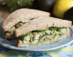Avocado chicken salad sandwich cut in half on a blue plate.