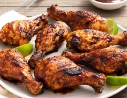 Platter of grilled chicken drumsticks with BBQ sauce.