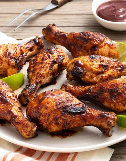 Platter of grilled chicken drumsticks with BBQ sauce.