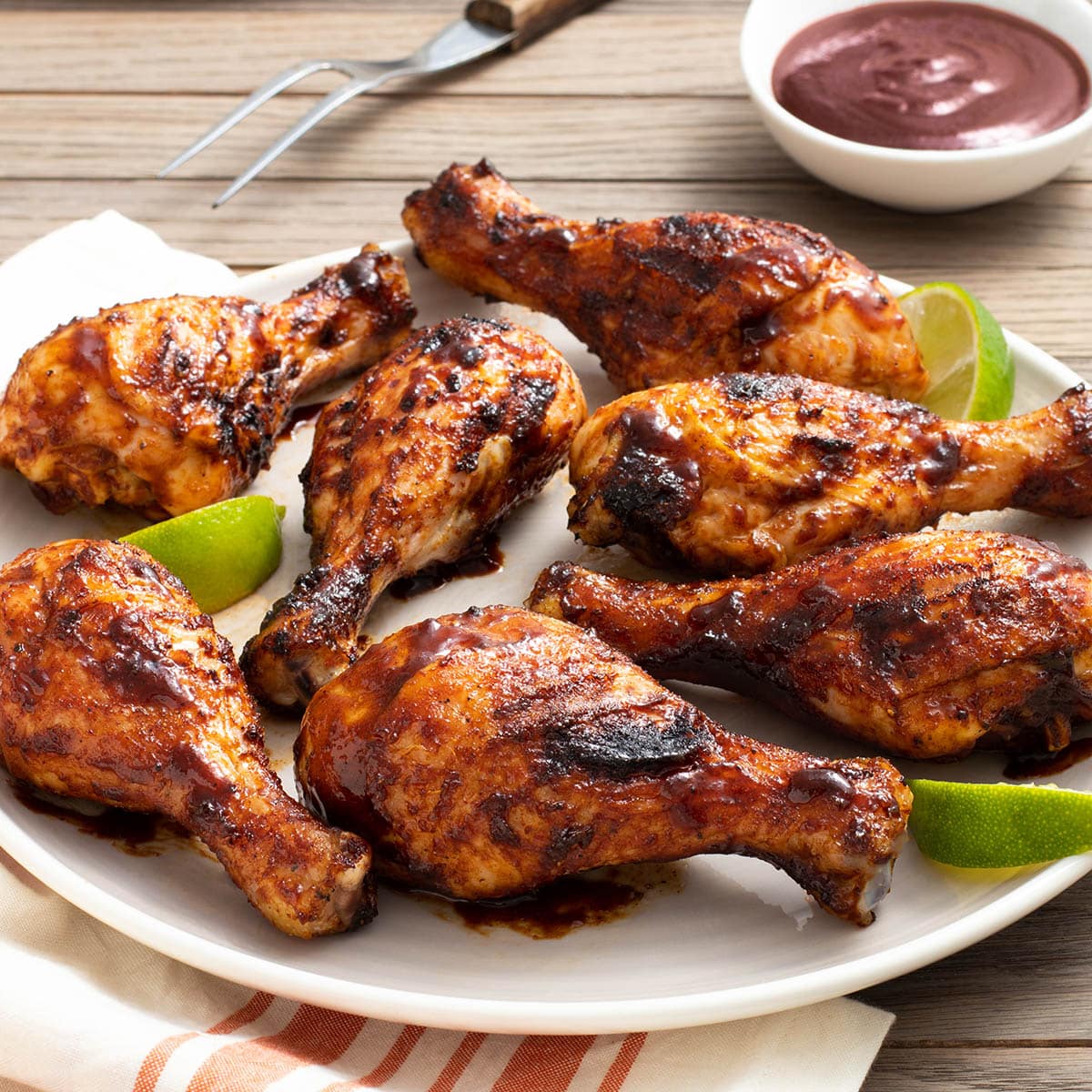 Platter of grilled chicken drumsticks with BBQ sauce.