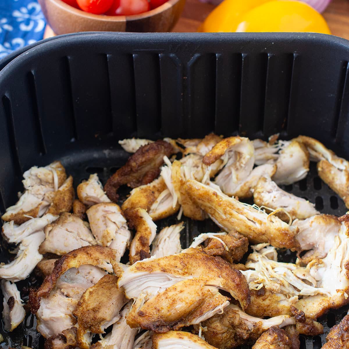 Shredded shawarma chicken in air fryer basket.