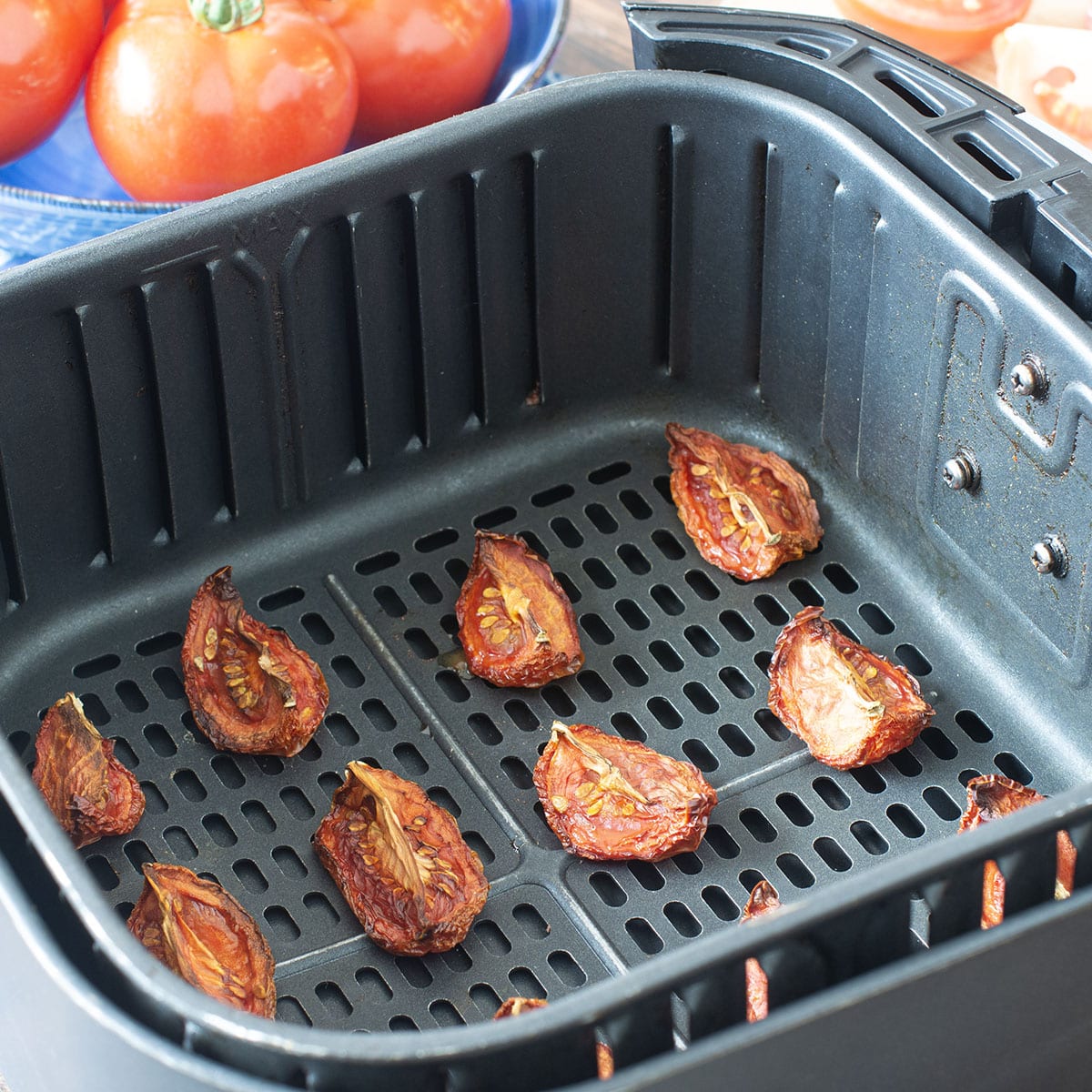 Dried tomato wedges in the air fryer basket.