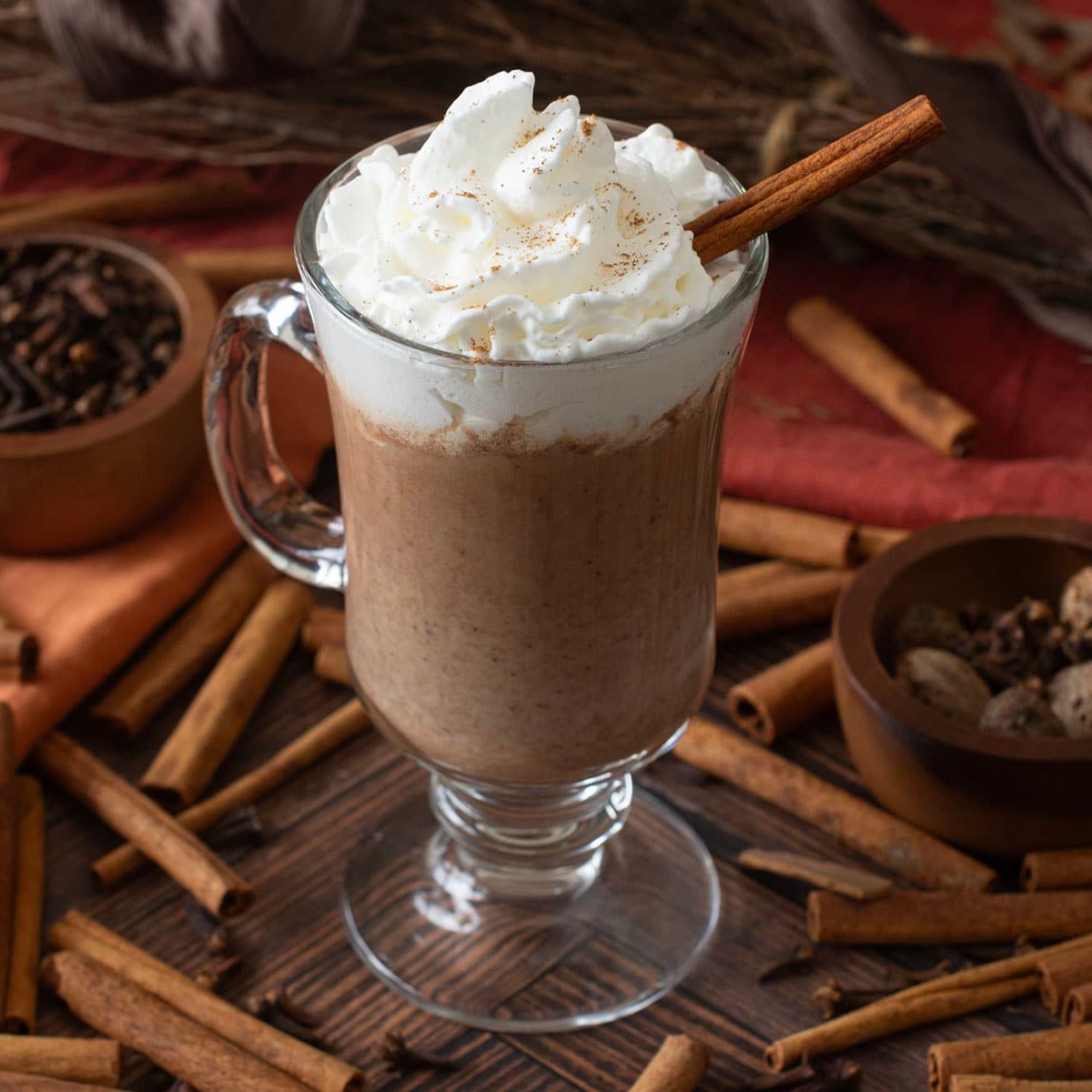 Glass mug with pumpkin hot chocolate topped with whipped cream.