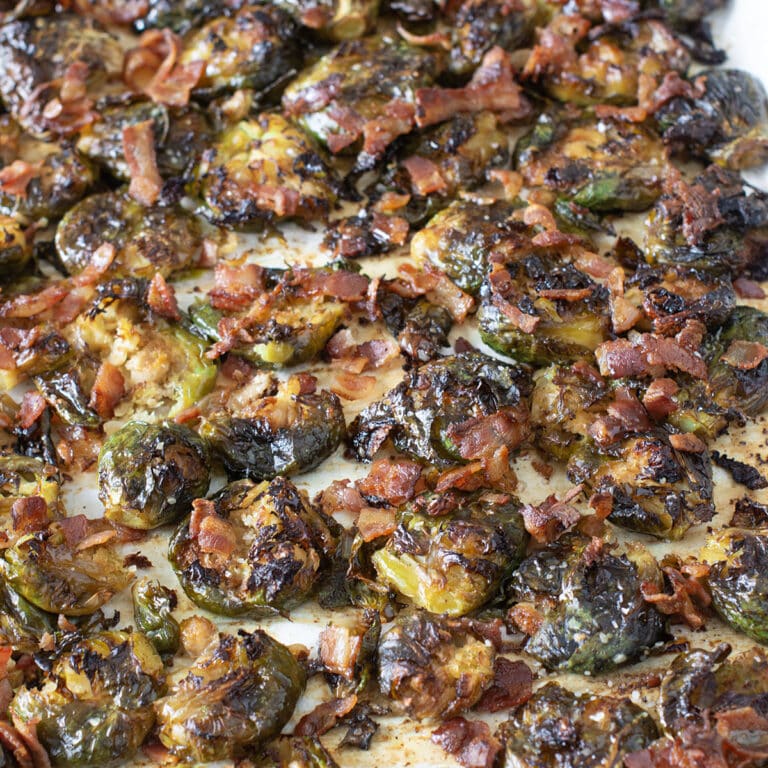 Crispy smashed Brussels sprouts with bacon on a baking sheet.