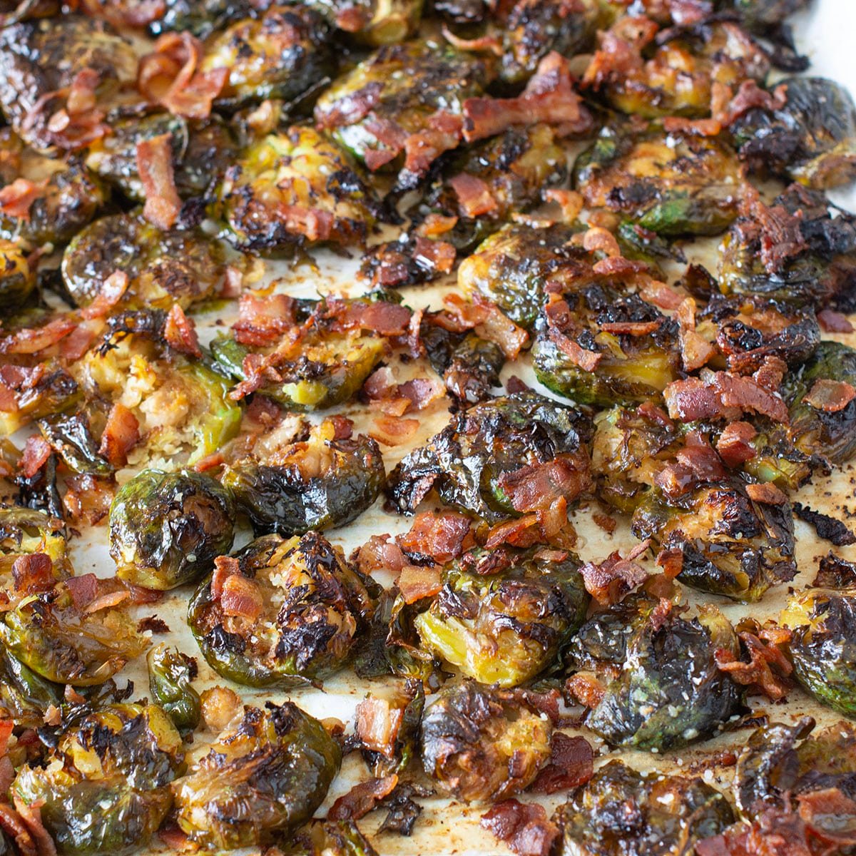 Crispy smashed Brussels sprouts with bacon on a baking sheet.