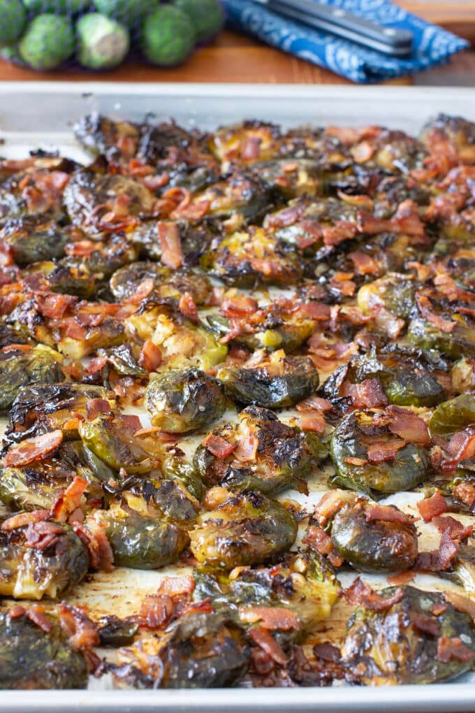 Crispy smashed Brussels sprouts with bacon on a baking sheet.