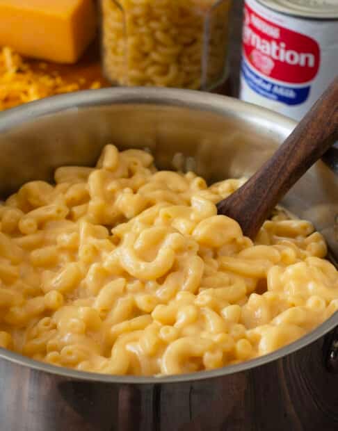 Macaroni and cheese in a pot with wooden spoon.