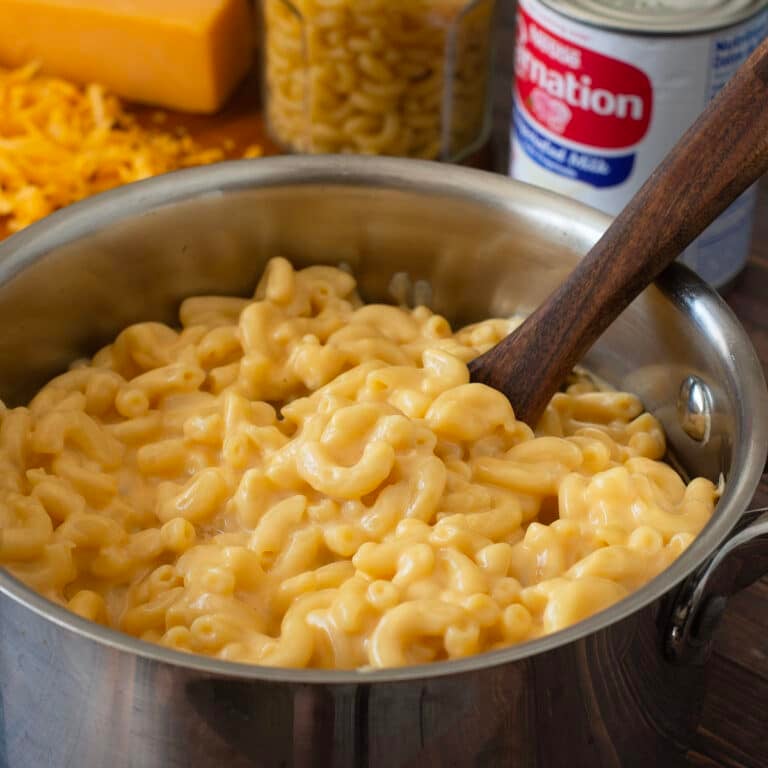 Macaroni and cheese in a pot with wooden spoon.