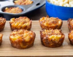 Macaroni and cheese cups on a cutting board.