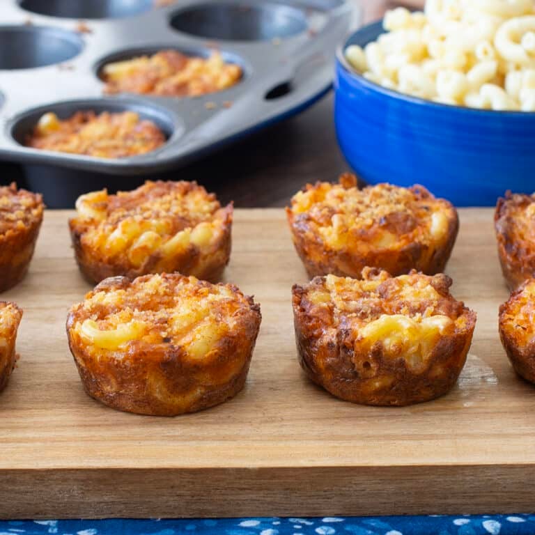 Macaroni and cheese cups on a cutting board.