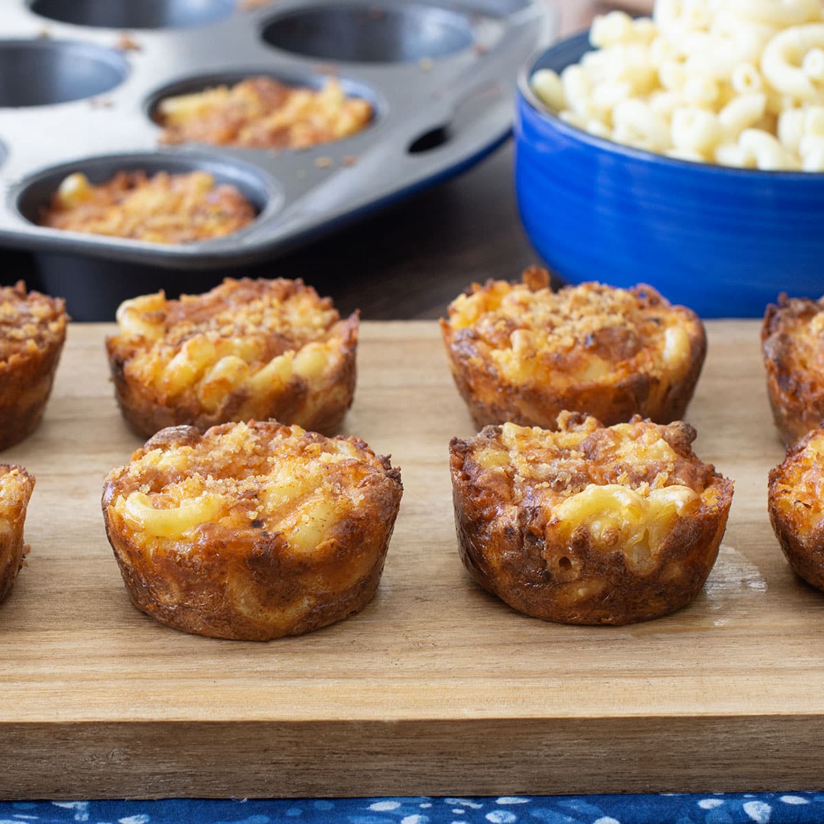 Macaroni and cheese cups on a cutting board.