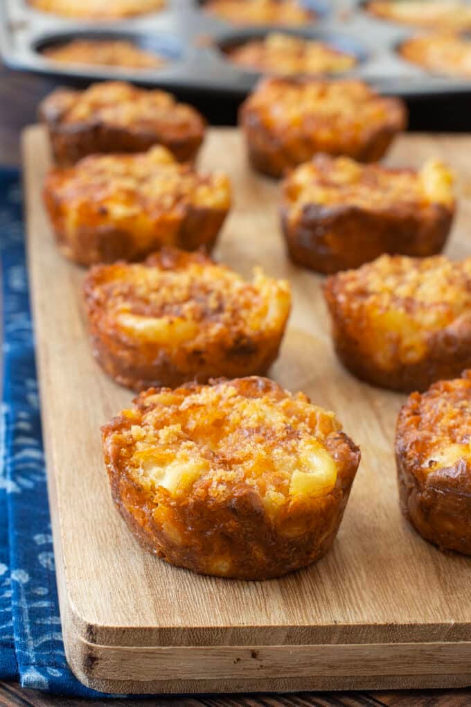 Macaroni and cheese cups on a cutting board.