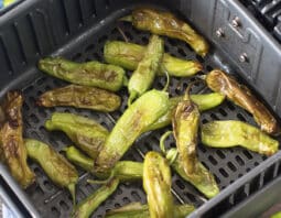 Blistered shishito peppers in the air fryer basket.