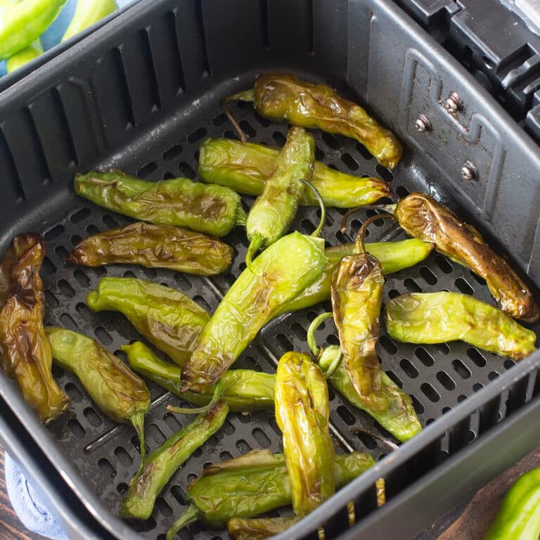 Blistered shishito peppers in the air fryer basket.