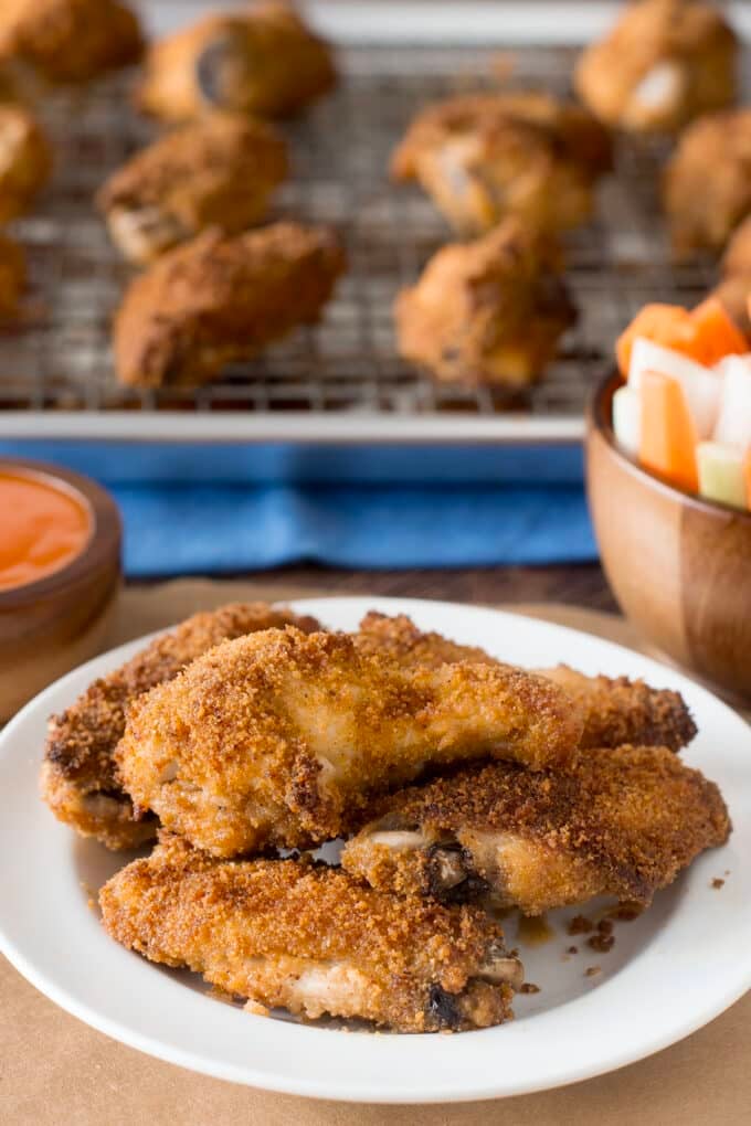 Breaded baked chicken wings on a white plate.