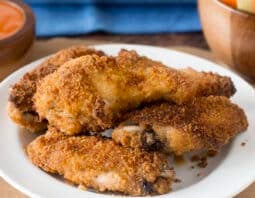 Breaded baked chicken wings on a white plate.