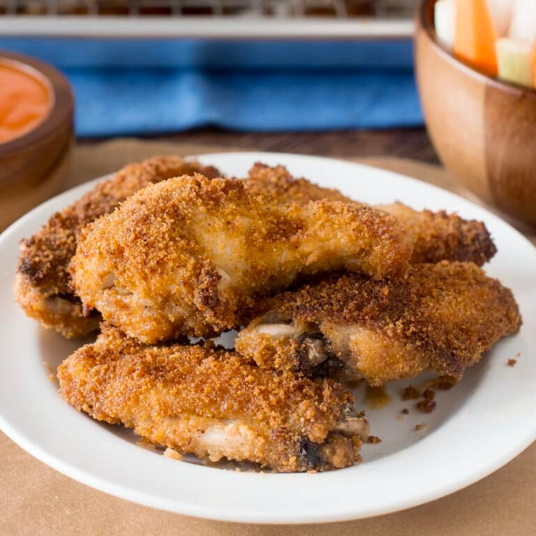 Breaded baked chicken wings on a white plate.