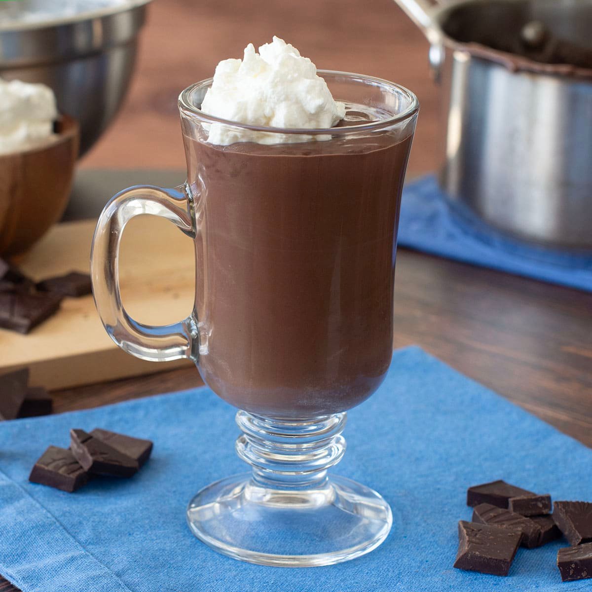 Glass mug of French hot chocolate topped with whipped cream.