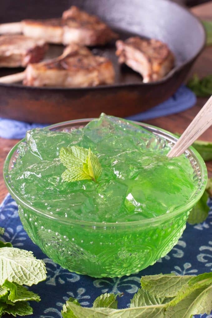 Glass bowl of mint jelly with spoon.