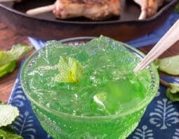 Glass bowl of mint jelly with spoon.