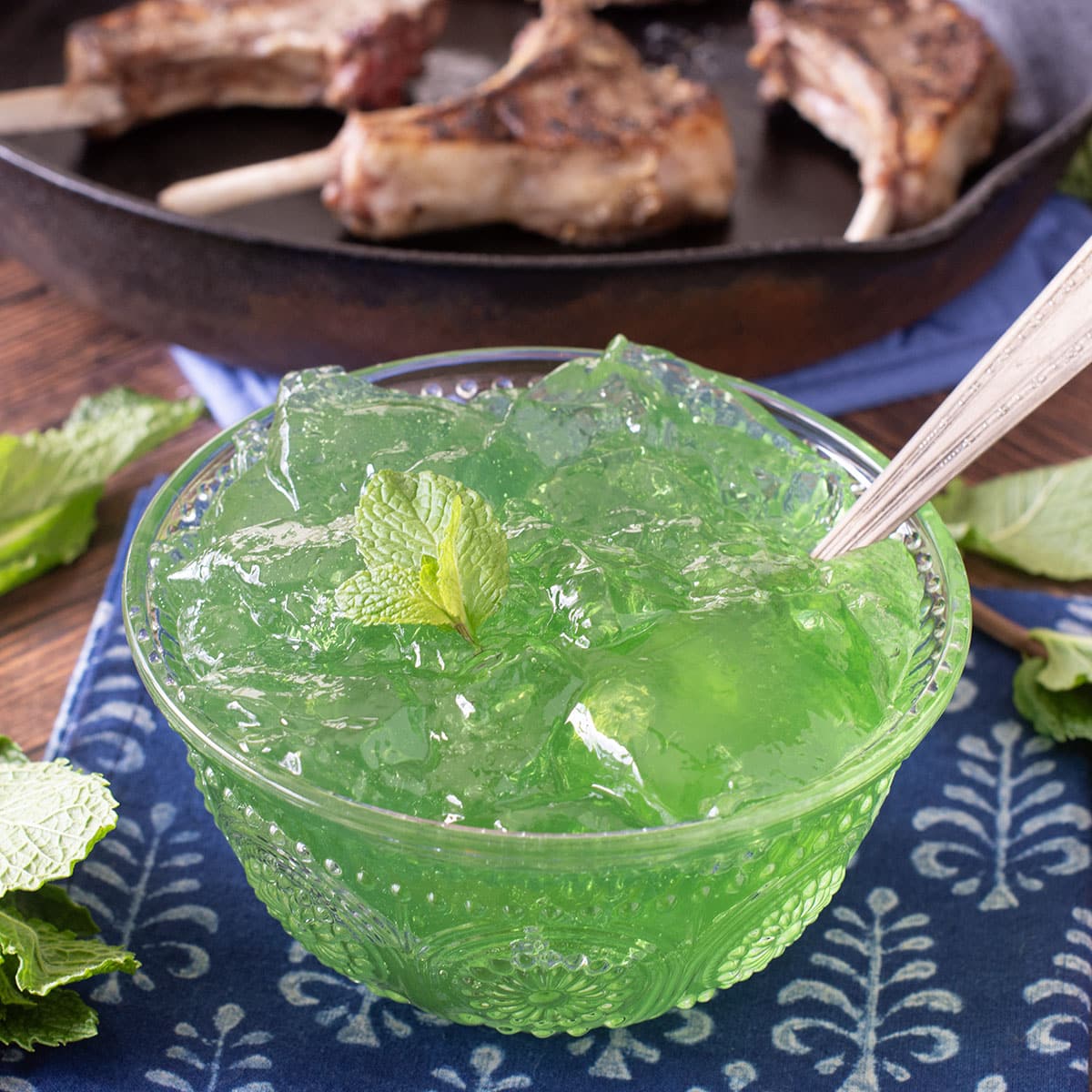 Glass bowl of mint jelly with spoon.