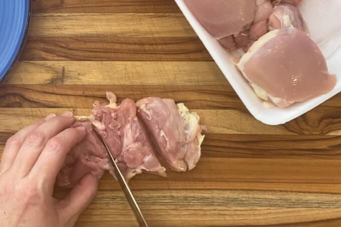 Cutting boneless skinless chicken thighs into boneless wings.