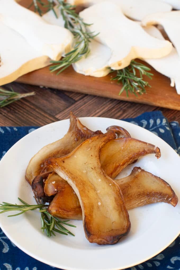 White plate with pan fried king oyster mushroom slices.