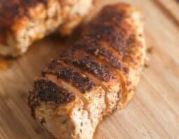 Sliced blackened chicken breasts on cutting board.