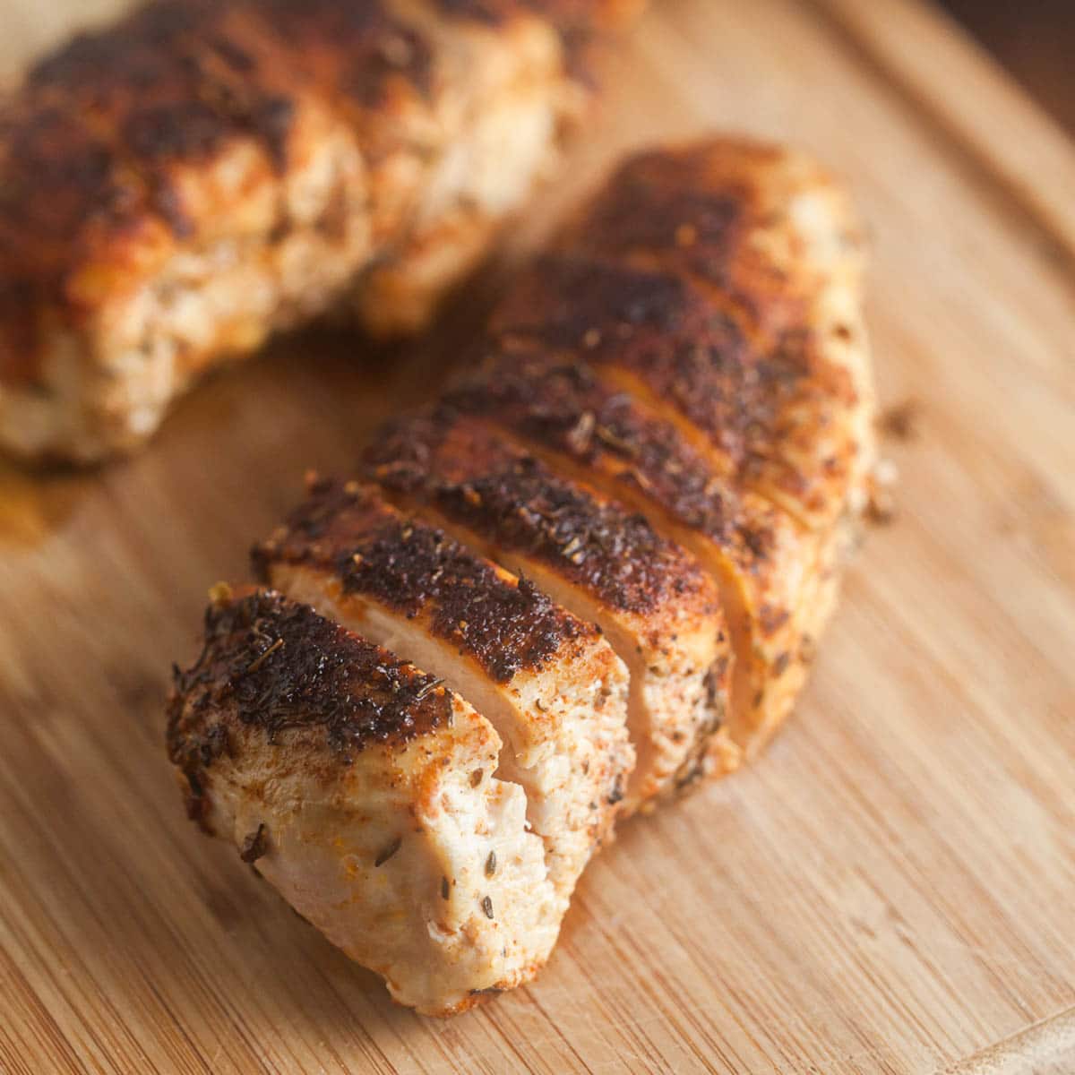 Sliced blackened chicken breasts on cutting board.