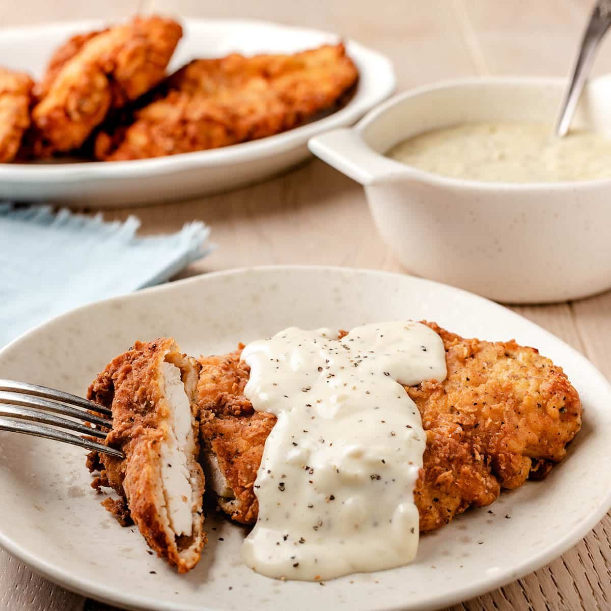 Fried chicken cutlet with country gravy on a plate with fork.