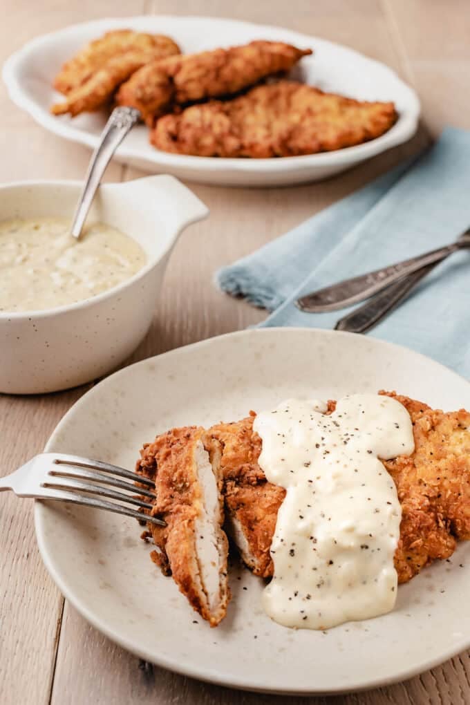 Fried chicken cutlet with country gravy on a plate with fork.