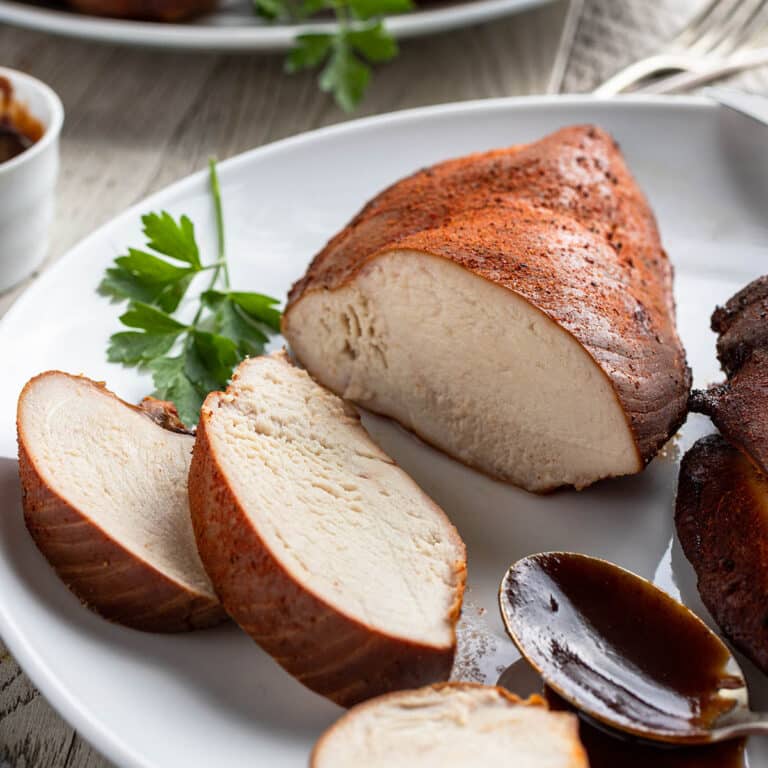 Smoked chicken breasts on plate with slices cut.