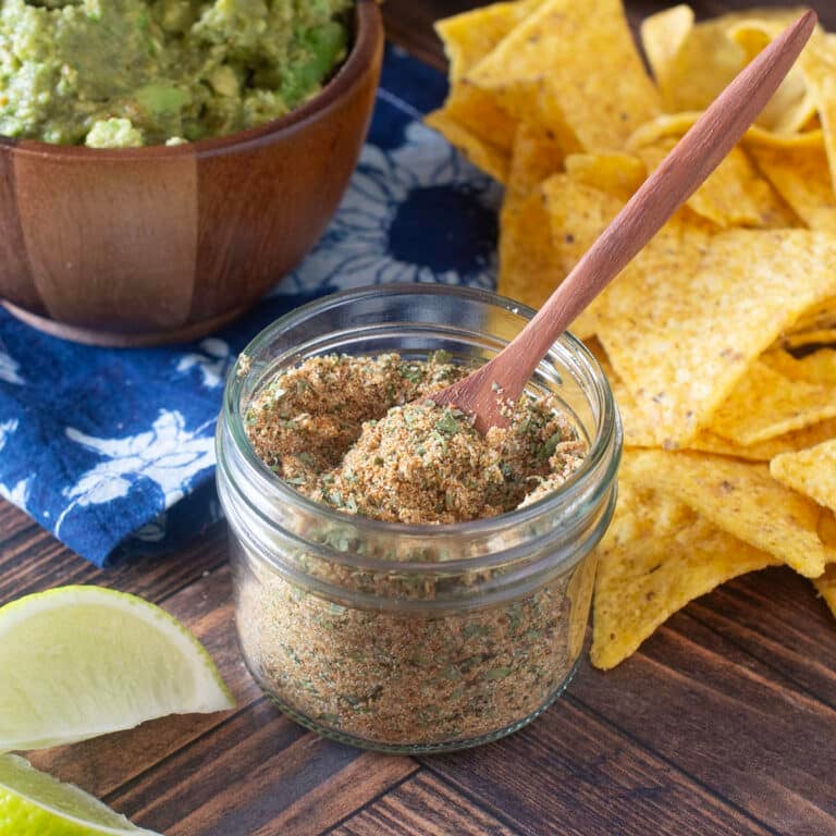 Glass jar with little wooden spoon of guacamole seasoning.