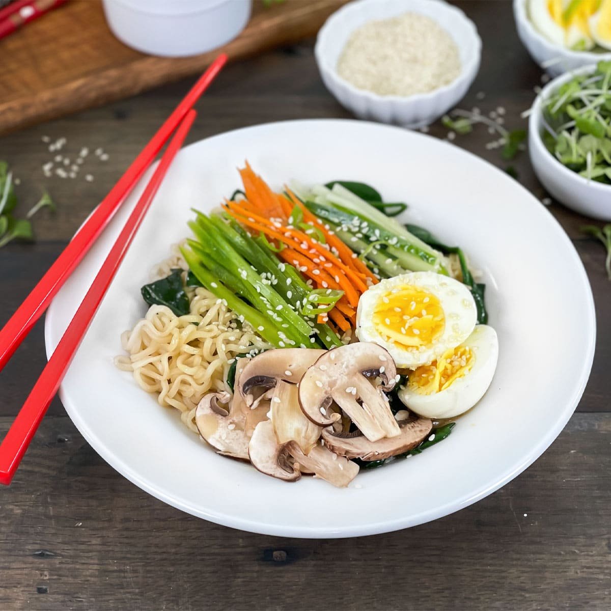 White bowl of ramen with veggies and hard boiled egg on top.