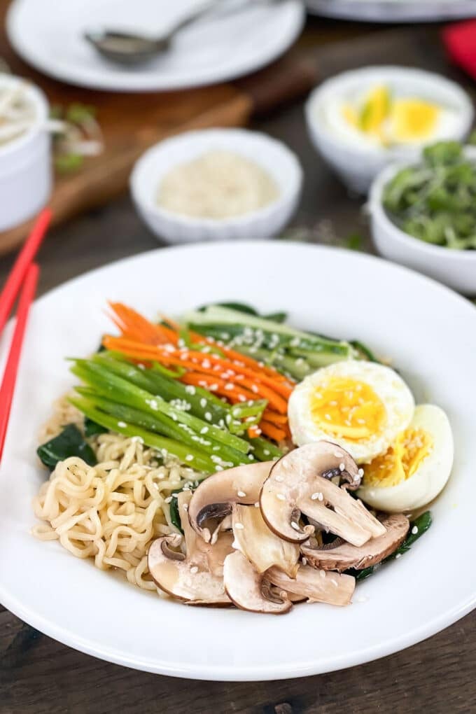 White bowl of ramen with veggies and hard boiled egg on top.