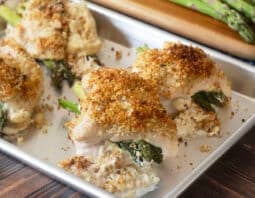 Whit platter with 4 asparagus stuffed chicken breasts with breadcrumb topping.