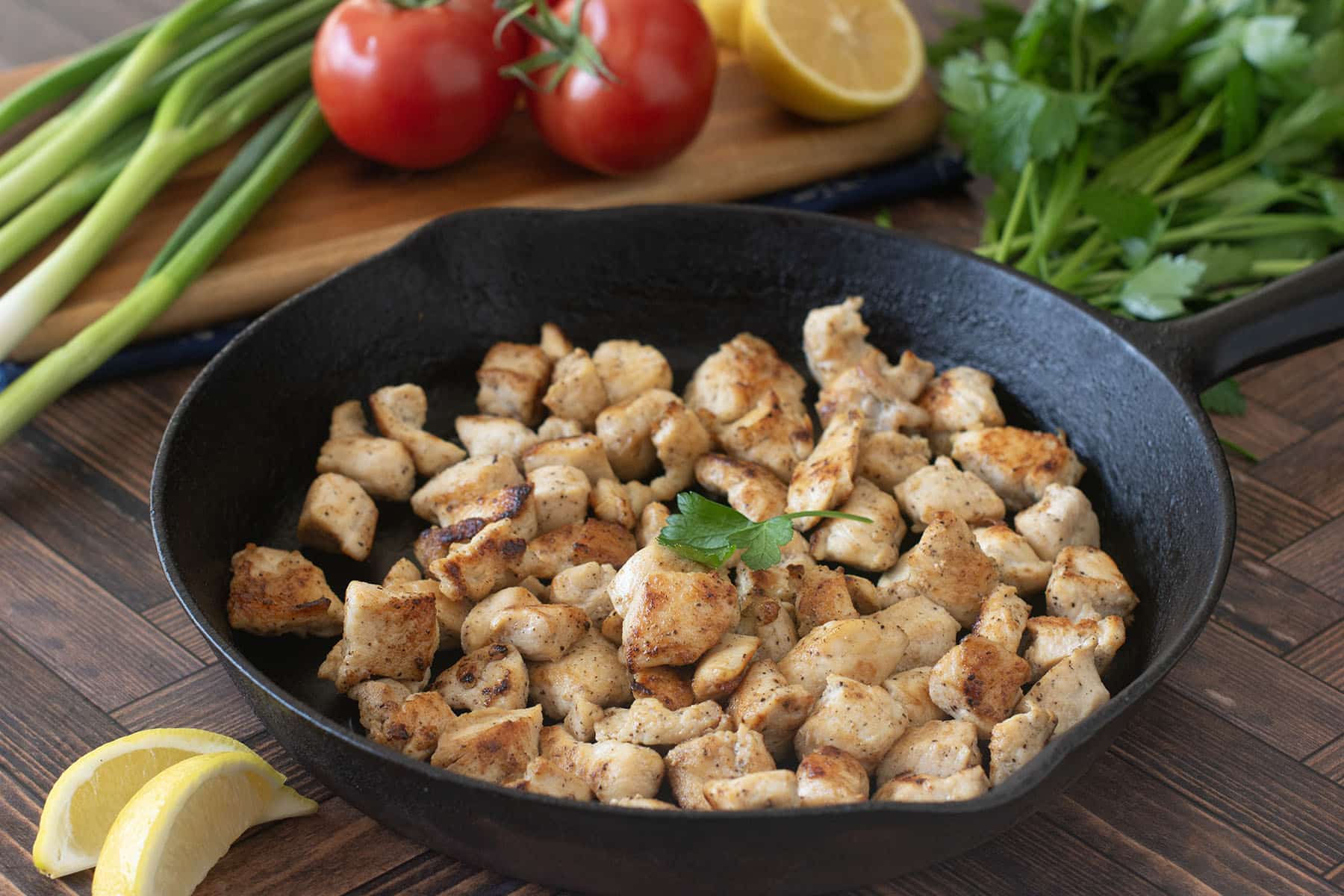 Bite-sized cubes of cooked chicken breast in a cast iron skillet.