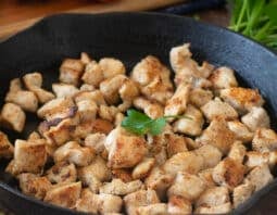 Cooked bite-sized chicken pieces in a cast iron skillet.