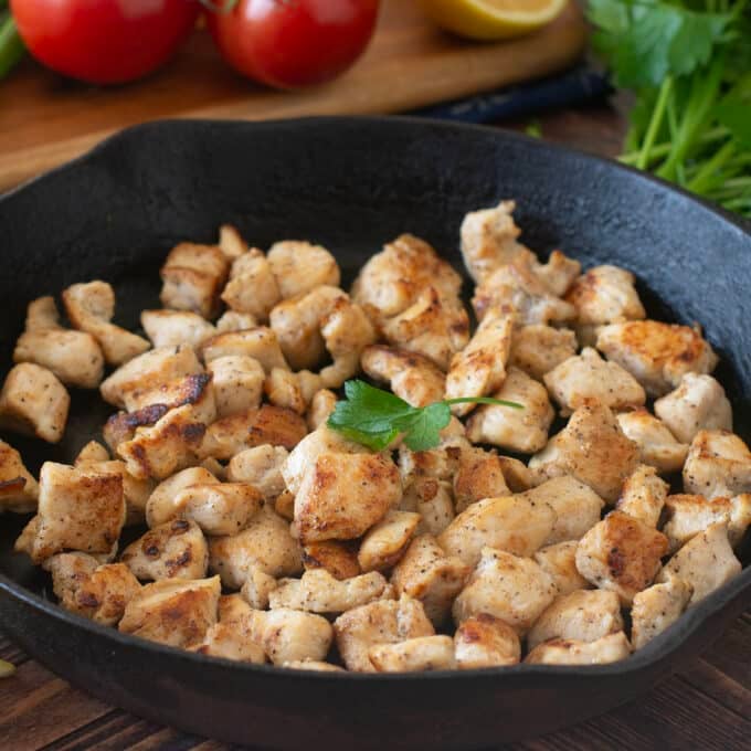 Cooked bite-sized chicken pieces in a cast iron skillet.