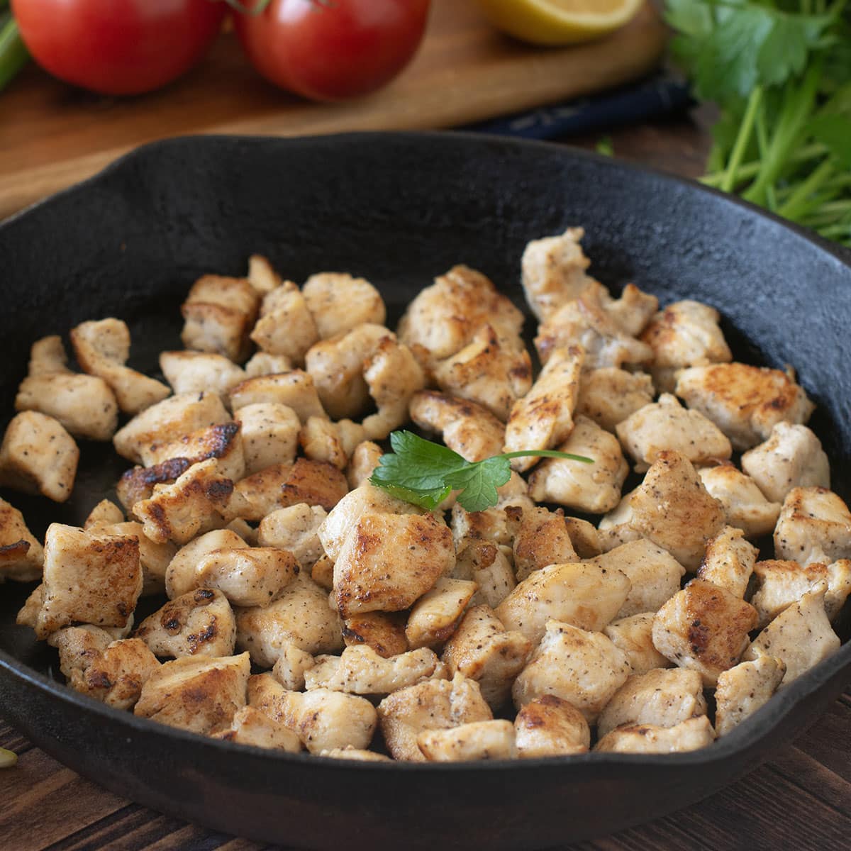 Cooked bite-sized chicken pieces in a cast iron skillet.