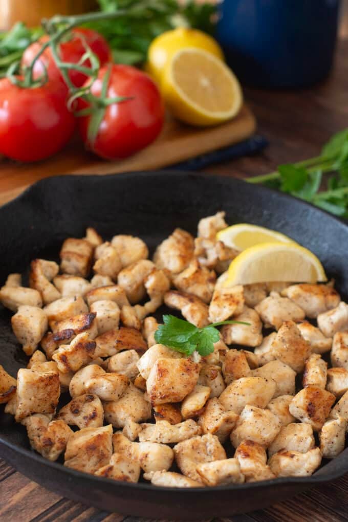 Cooked bite-sized chicken pieces in a cast iron skillet.