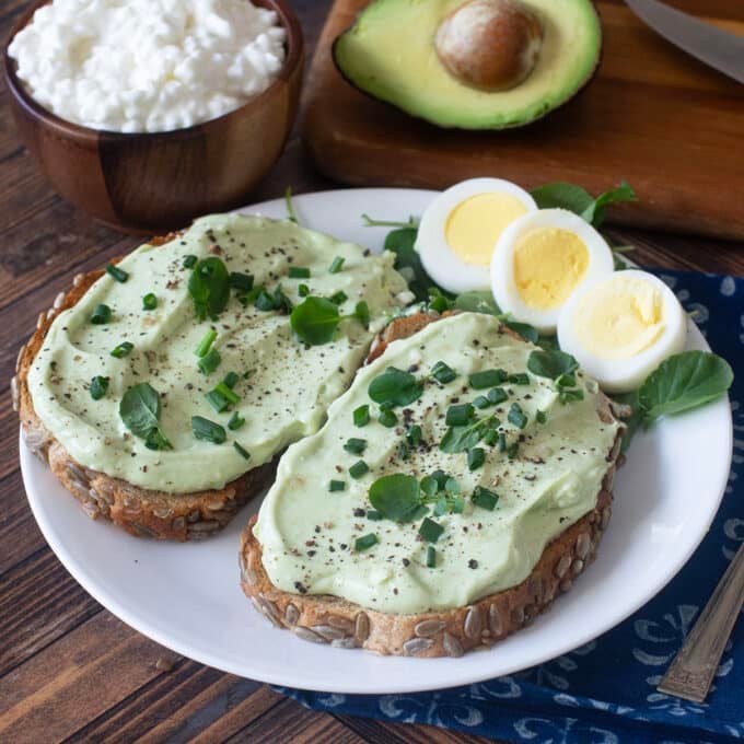 Whipped avocado cottage cheese on toast with hard boiled egg beside.