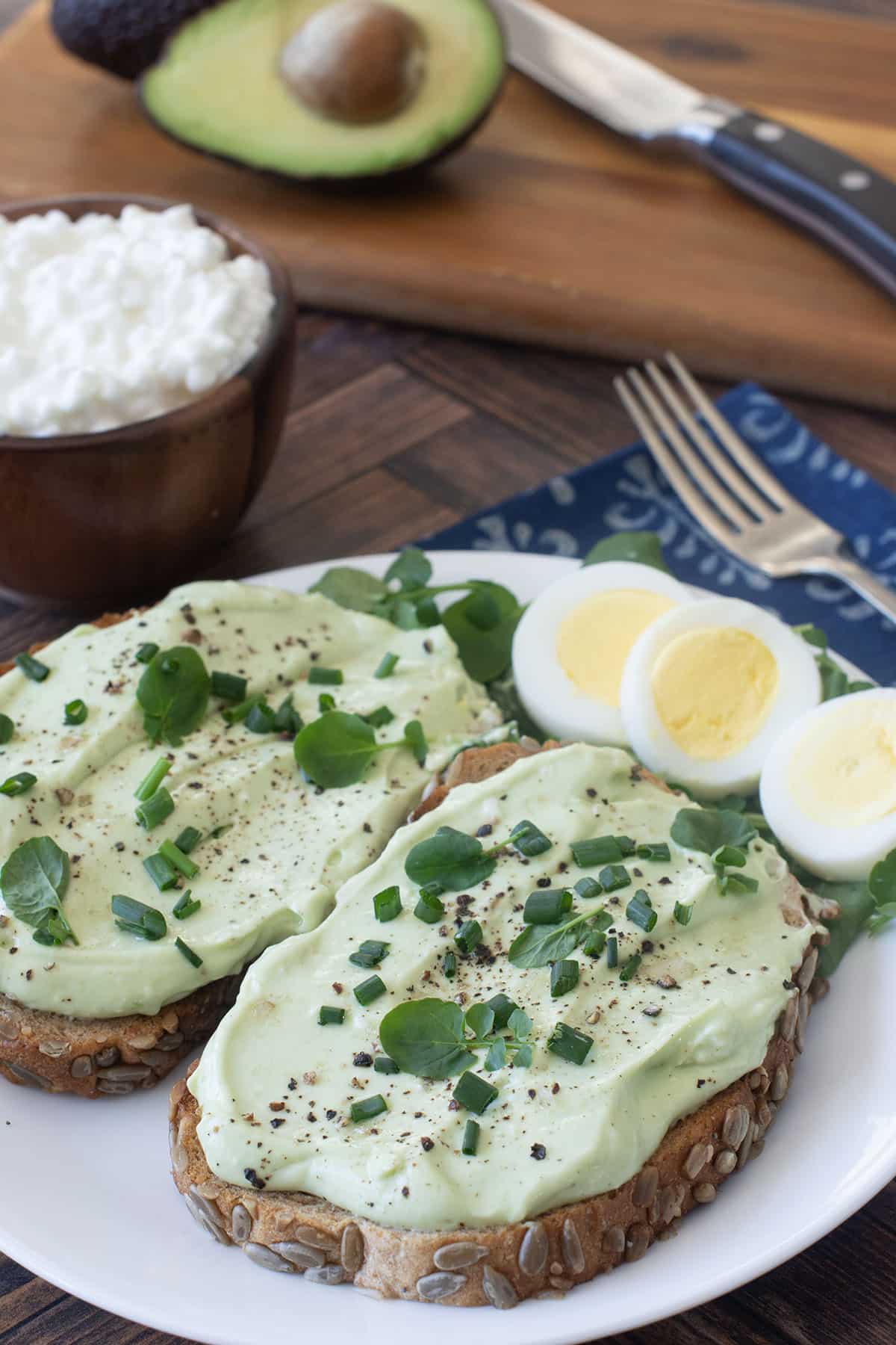 Whipped avocado cottage cheese on toast with hard boiled egg beside.