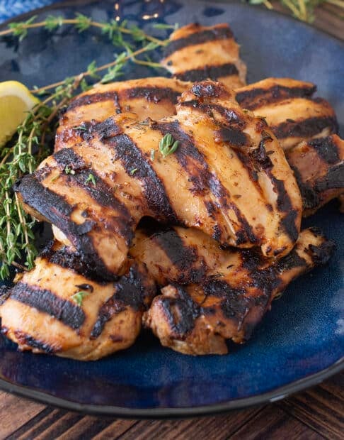 Grilled chicken thighs on blue plate.