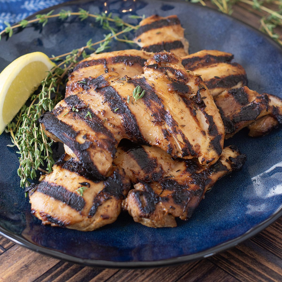Grilled chicken thighs on blue plate.