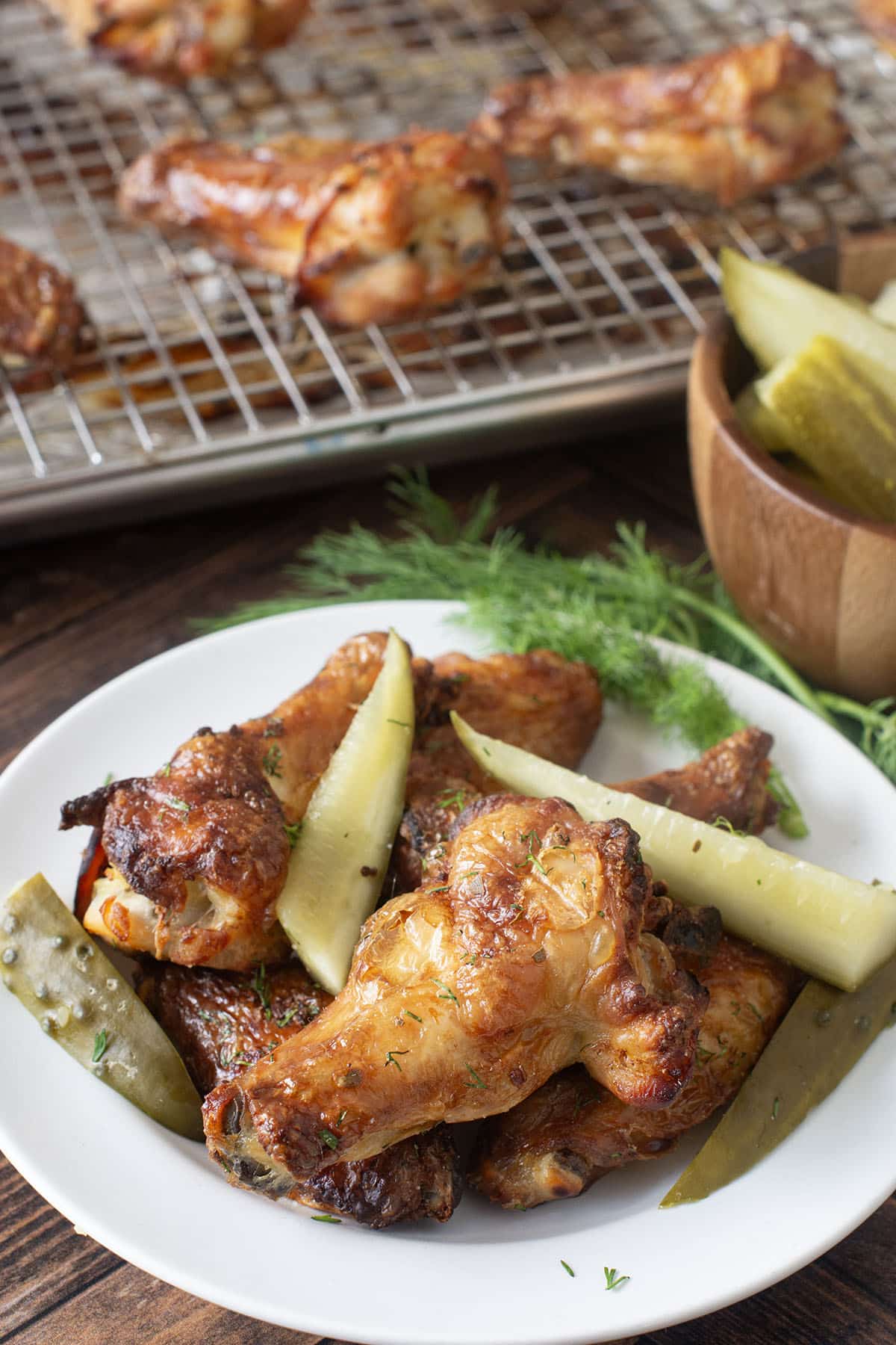 Plate of baked chicken wings and pickles.