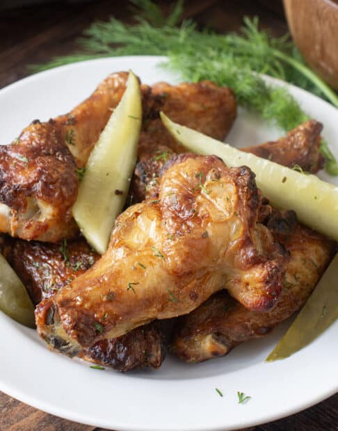 Plate of baked chicken wings and pickles.