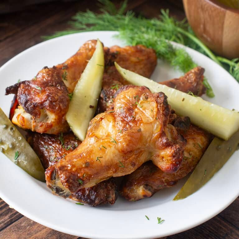 Plate of baked chicken wings and pickles.